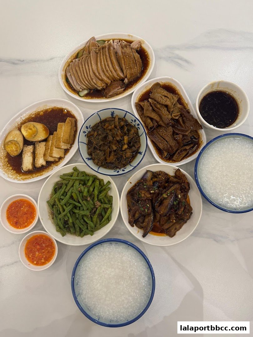 A spread of Teochew porridge with various side dishes including braised duck, tofu, eggs, and vegetables.