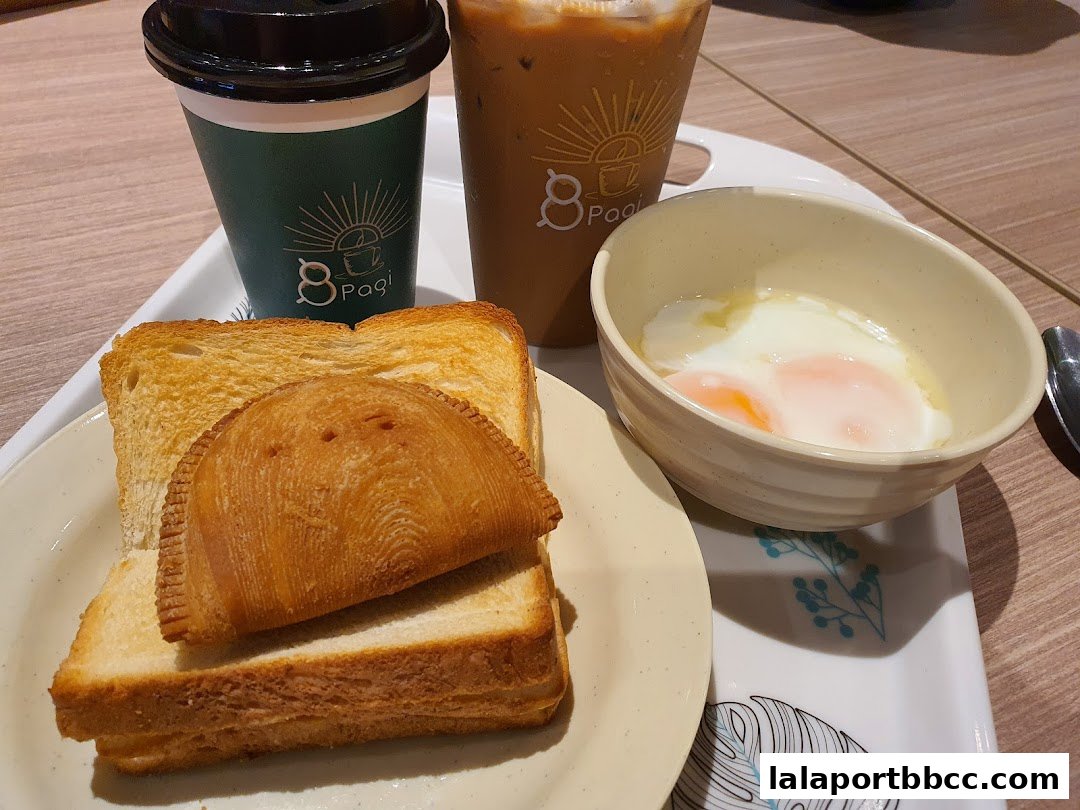 A tray with toast, a pastry, soft-boiled eggs, and two drinks from 8 Pagi.