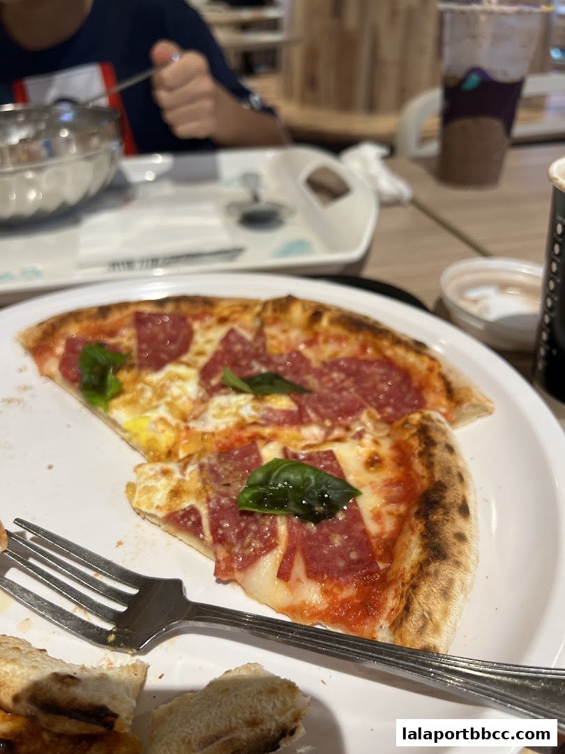 A close-up of a delicious pepperoni and basil pizza with a fork on a white plate.