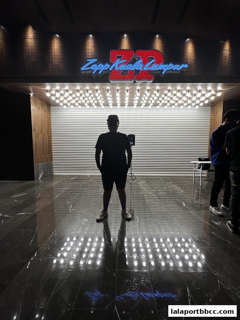 A person stands in front of the illuminated Zepp Kuala Lumpur entrance.