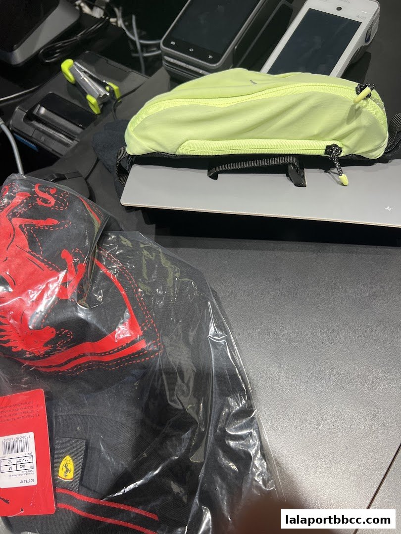 A black Puma t-shirt with red Ferrari branding and a neon yellow waist bag.