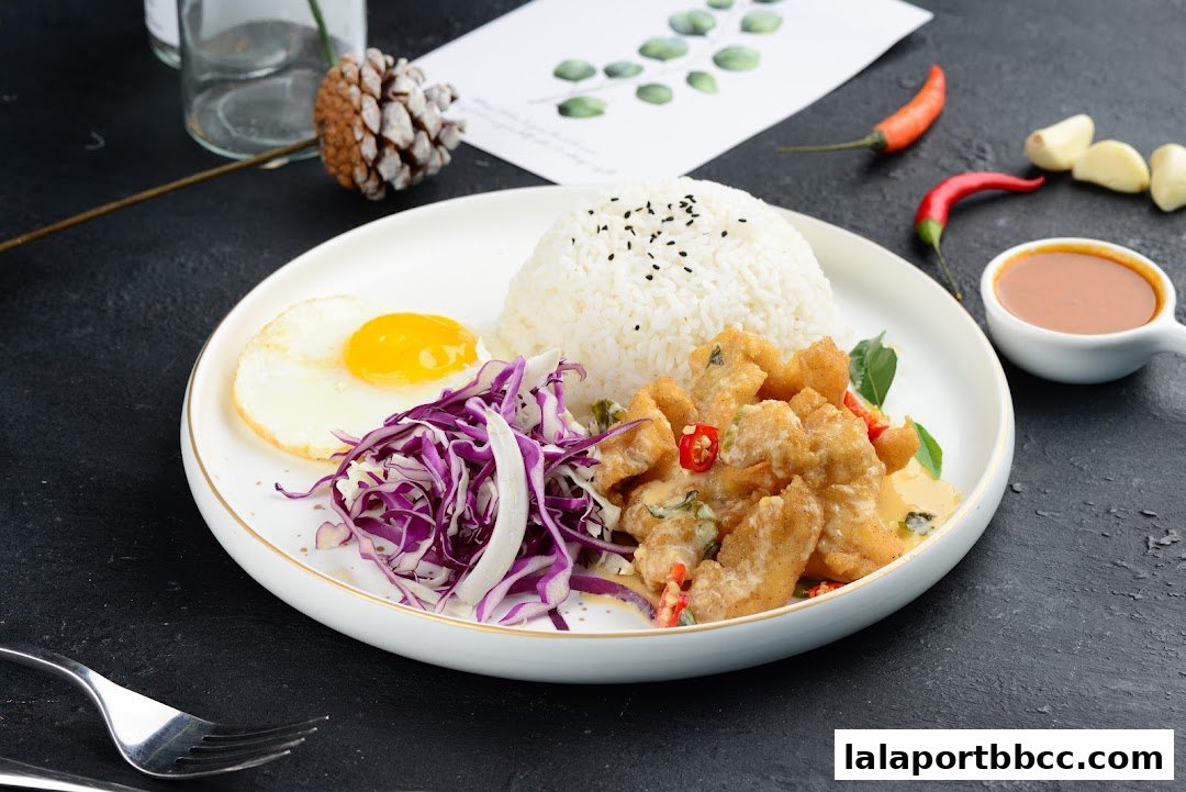 A delicious meal featuring fried chicken, rice, a fried egg, and salad with a side of sauce.