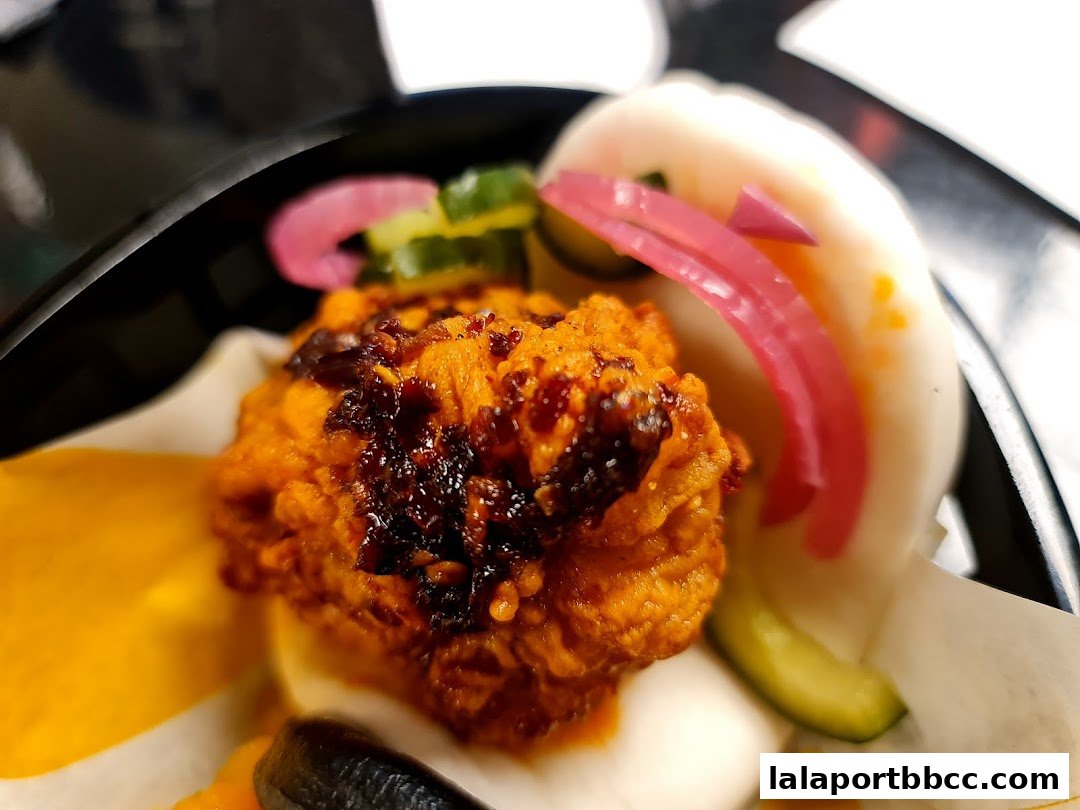 A close-up of a delicious bao bun with crispy filling and pickled toppings.