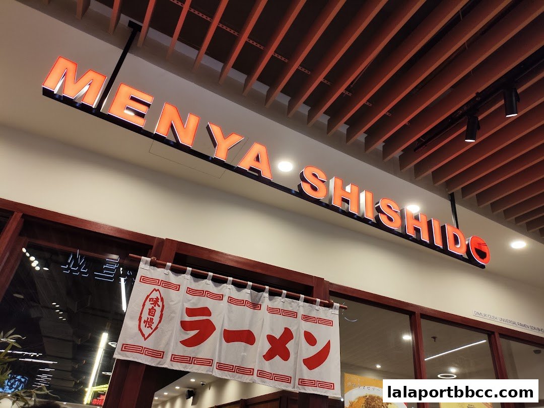 The illuminated sign for Menya Shishido above the shop entrance with a ramen banner.