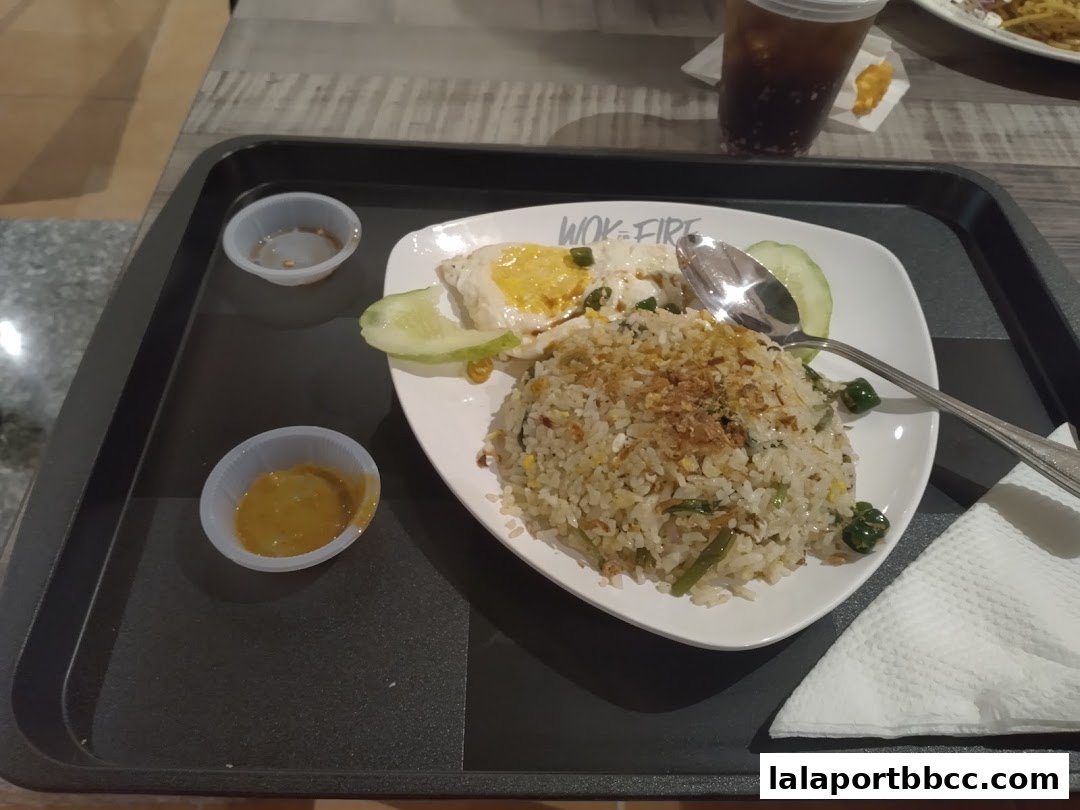 A plate of fried rice with a fried egg, cucumber slices, and dipping sauces.