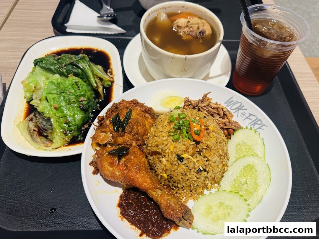 A plate of fried rice with fried chicken, lettuce, soup, and a drink.