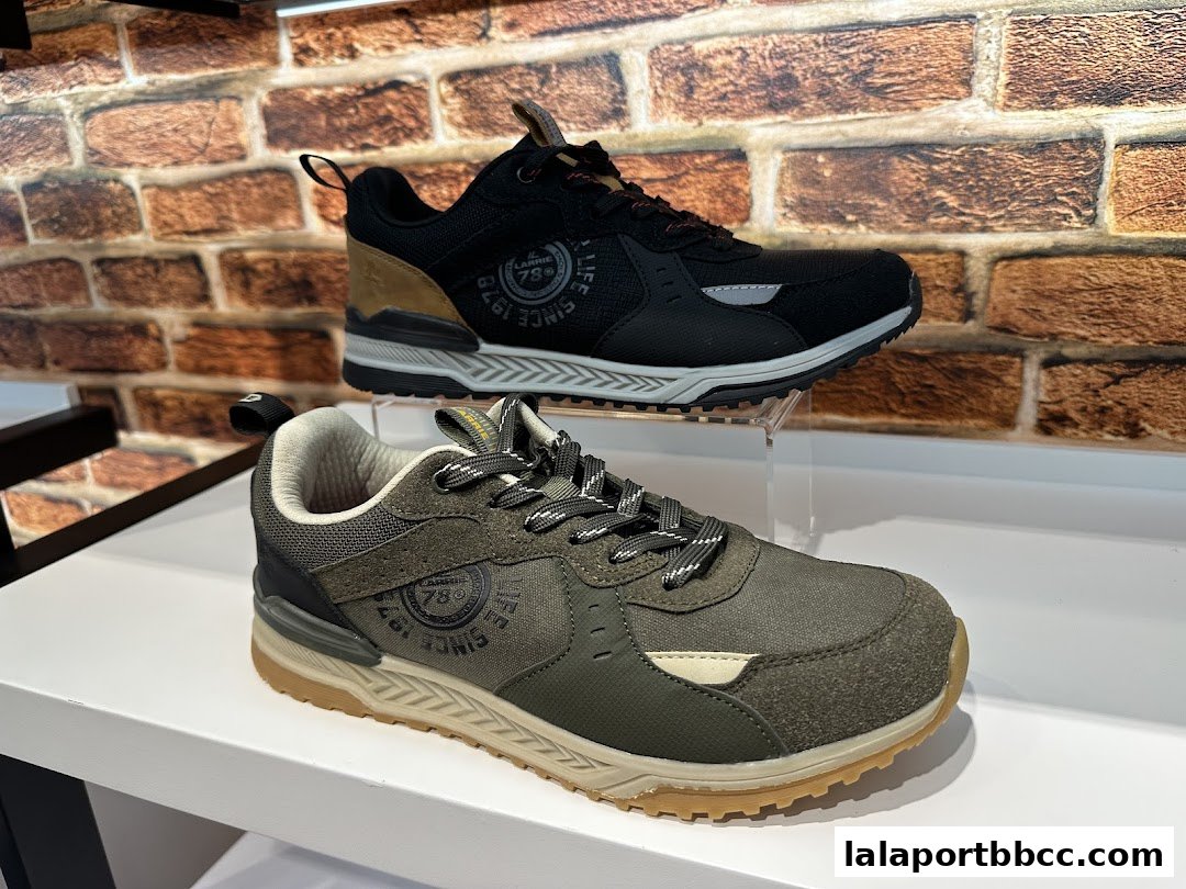 Two stylish Larrie sneakers, one black and one olive green, displayed on shelves.