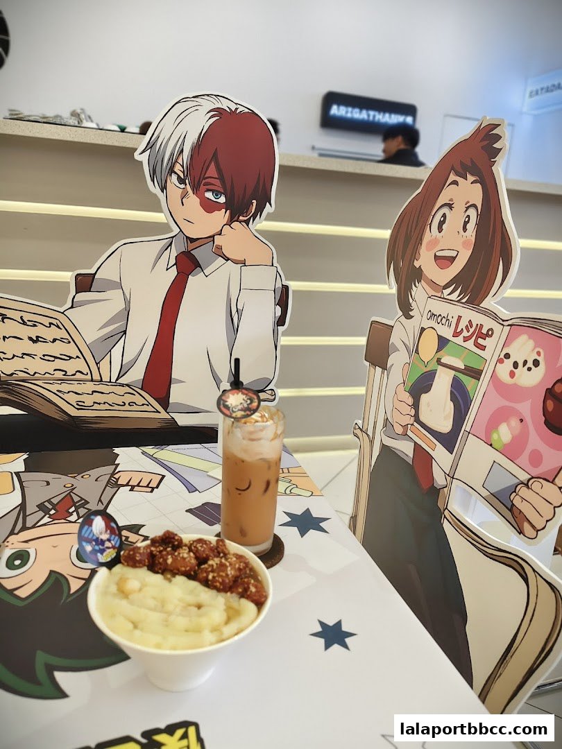 A table setting at Doko Koko with anime character cutouts, a drink, and a bowl of food.