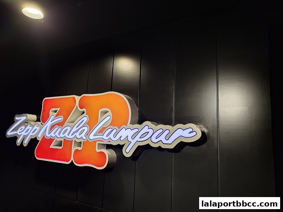 A neon sign for Zepp Kuala Lumpur is displayed on a dark, paneled wall.