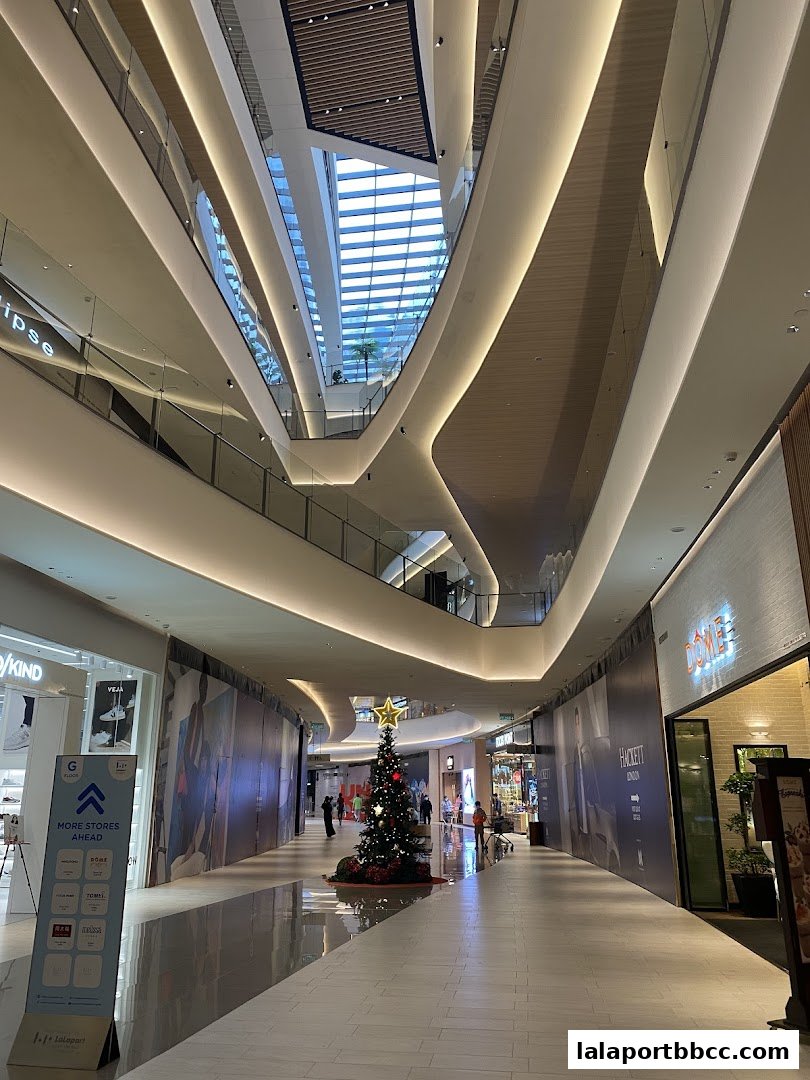 A wide view of a modern shopping mall interior with multiple levels and a Christmas tree.