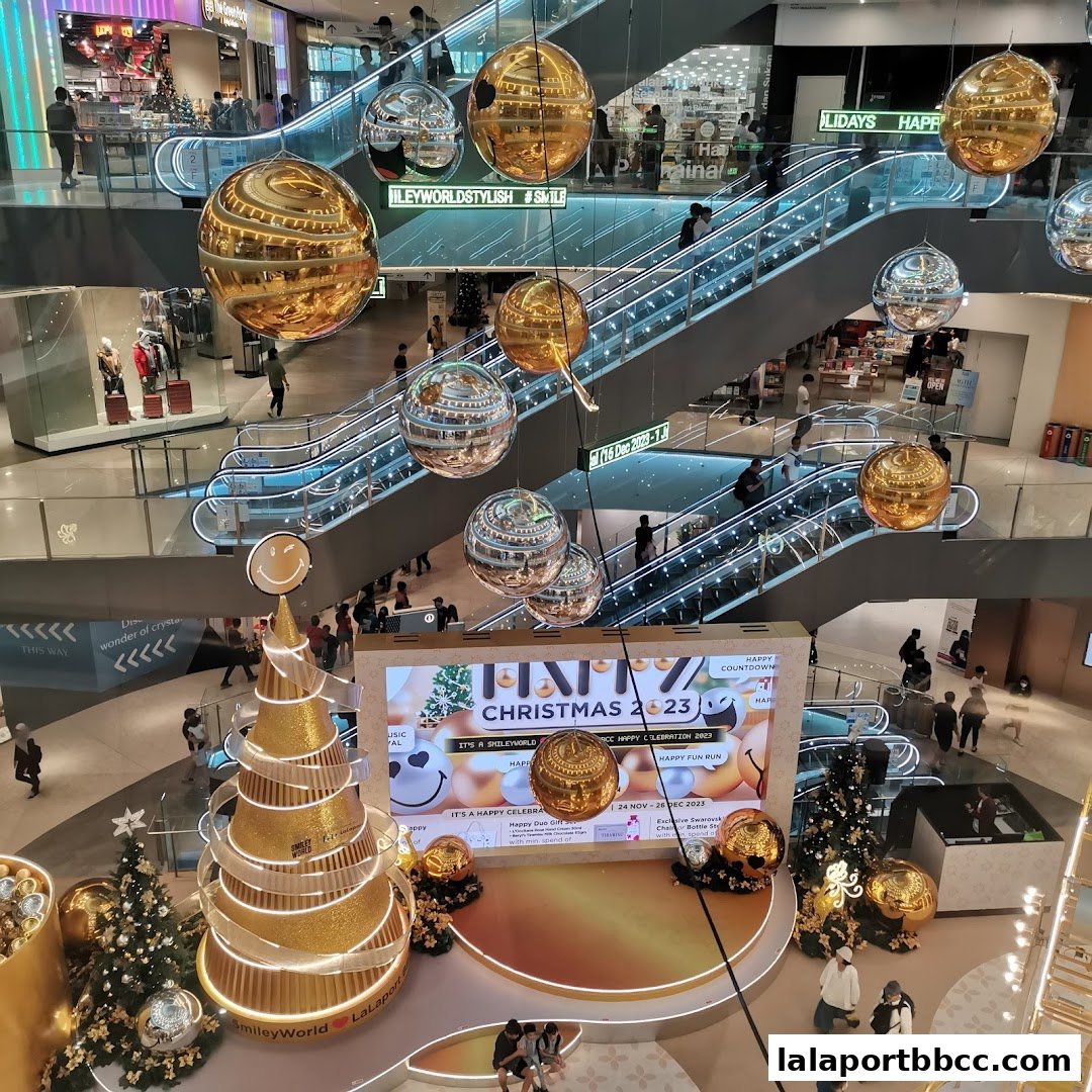 A festive Christmas display with a golden tree and large hanging ornaments in a shopping mall.