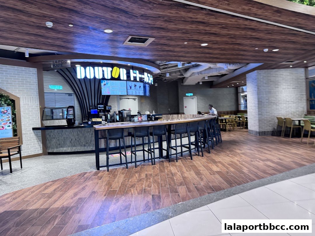 Interior view of a DOUTOR COFFEE shop with a counter, seating, and a menu board.