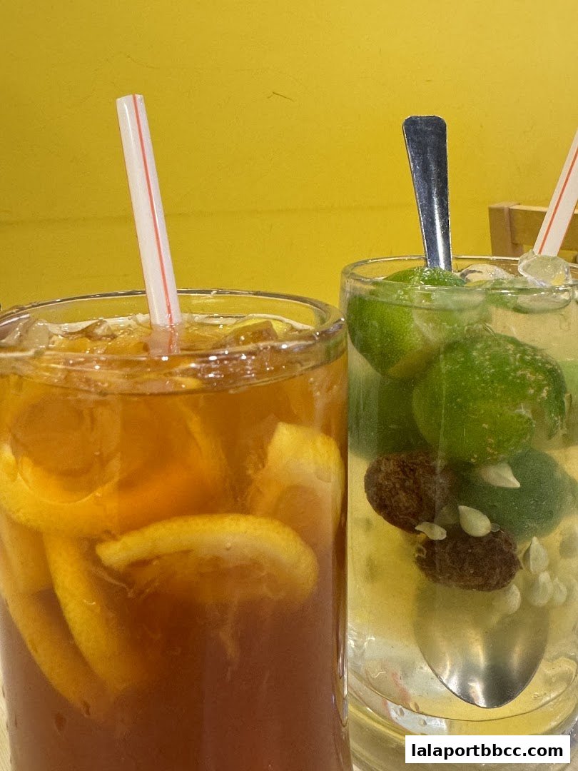 Two refreshing drinks, one iced tea with lemon slices and another with lime and dried fruits.