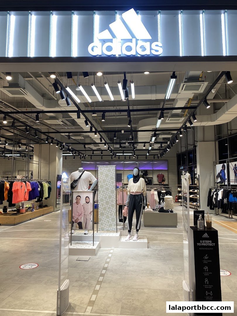 The entrance of an Adidas Originals store with mannequins displaying sportswear and the Adidas logo prominently displayed.
