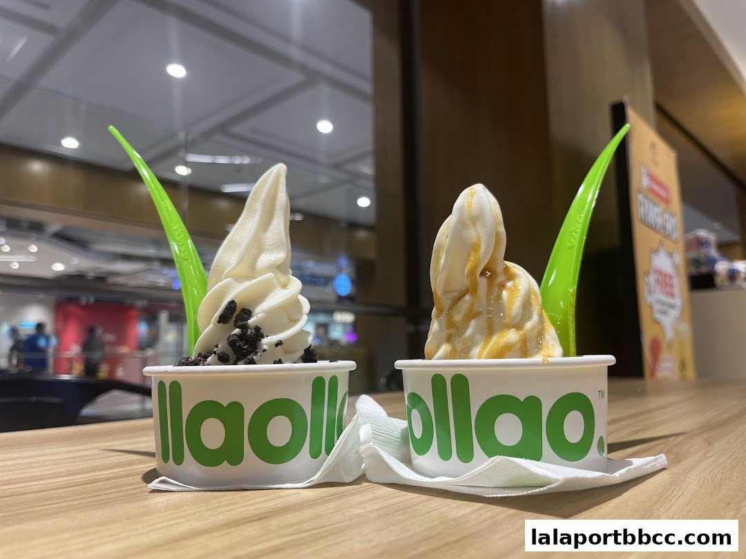 Two cups of llaollao frozen yogurt with toppings on a wooden table.