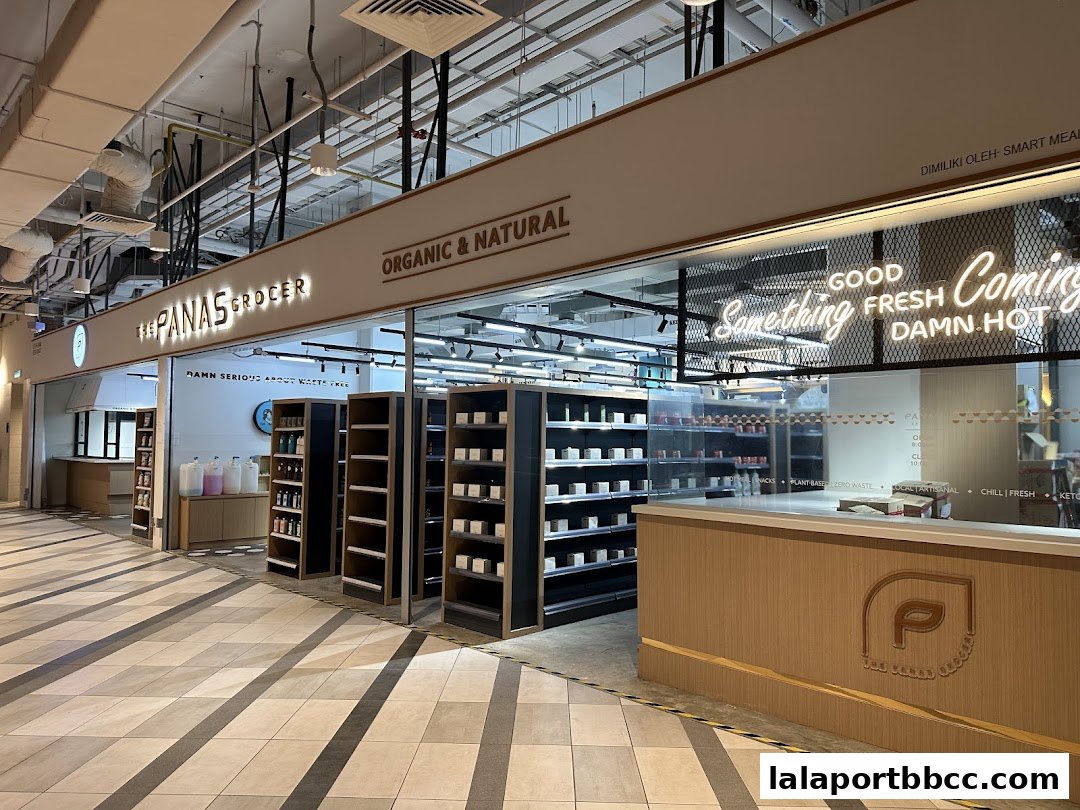 The Panas Grocer shop front with shelves stocked with products and a neon sign.