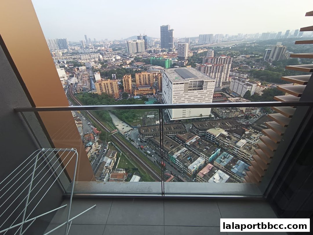 A panoramic view of a city skyline from a balcony with a clothes rack.