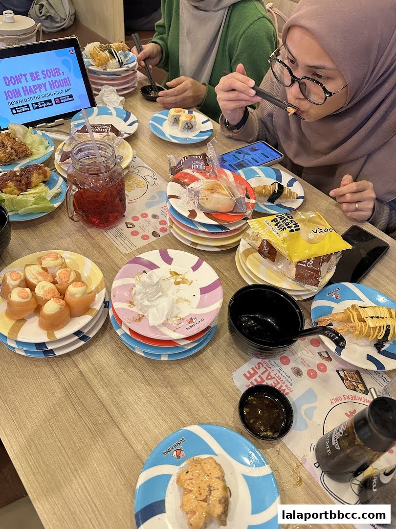 A table full of sushi plates, drinks, and people enjoying a meal at Sushi King.
