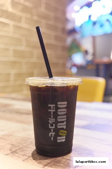 A close-up of an iced coffee in a clear plastic cup with the Doutor Coffee logo.