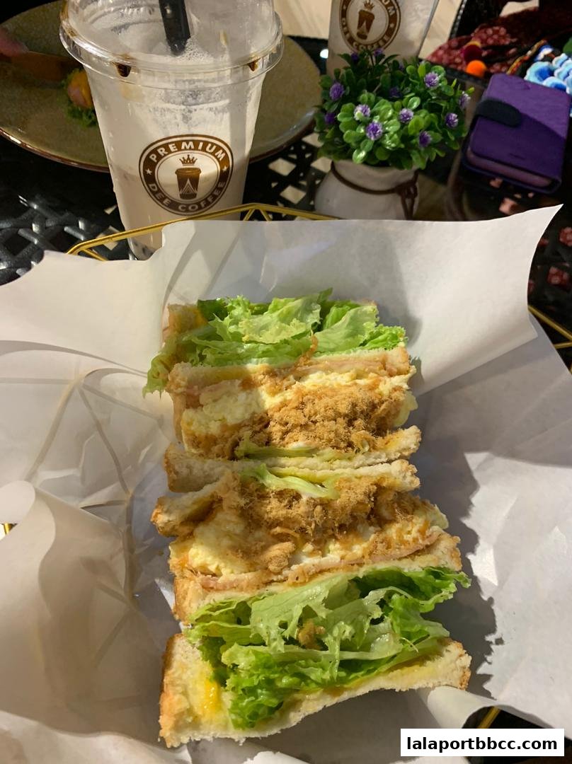A delicious sandwich with lettuce and shredded meat, served with a coffee drink.
