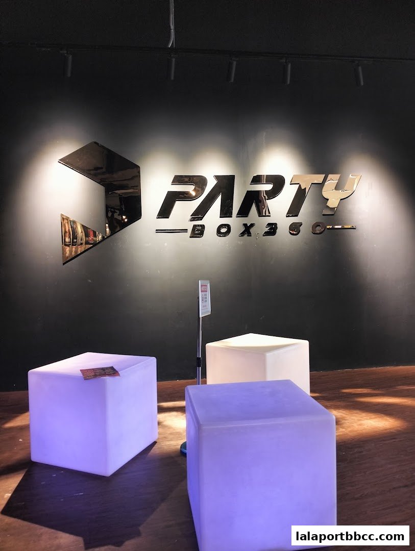 The PartyBox 360 logo is displayed on a dark wall with illuminated cube seating.