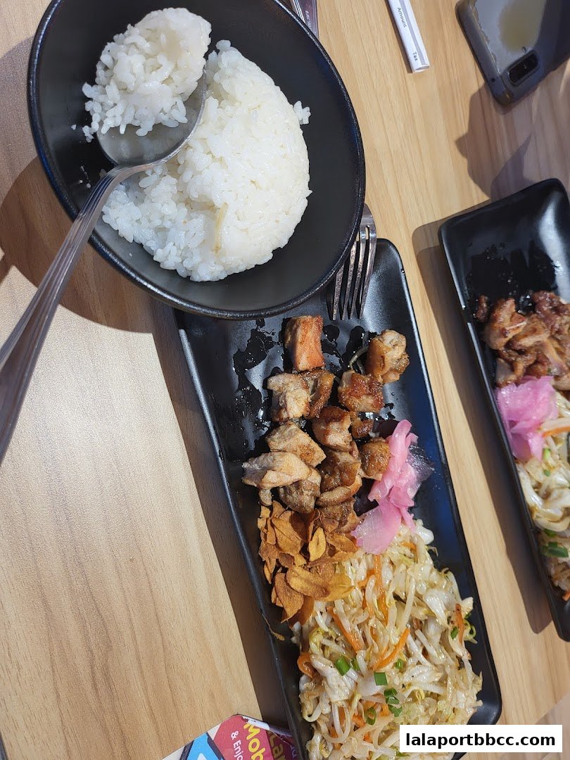 A close-up of a teppanyaki meal with rice, grilled meat, and stir-fried vegetables.