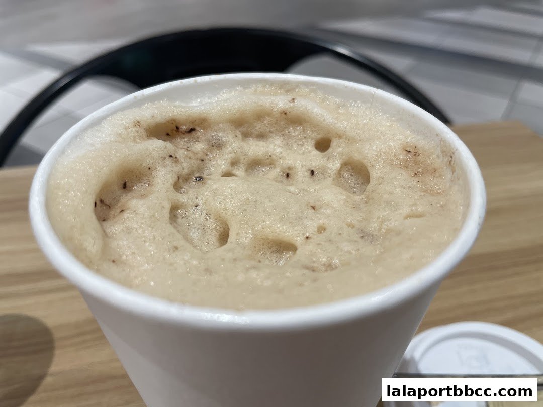 A close-up shot of a frothy beverage in a white paper cup.