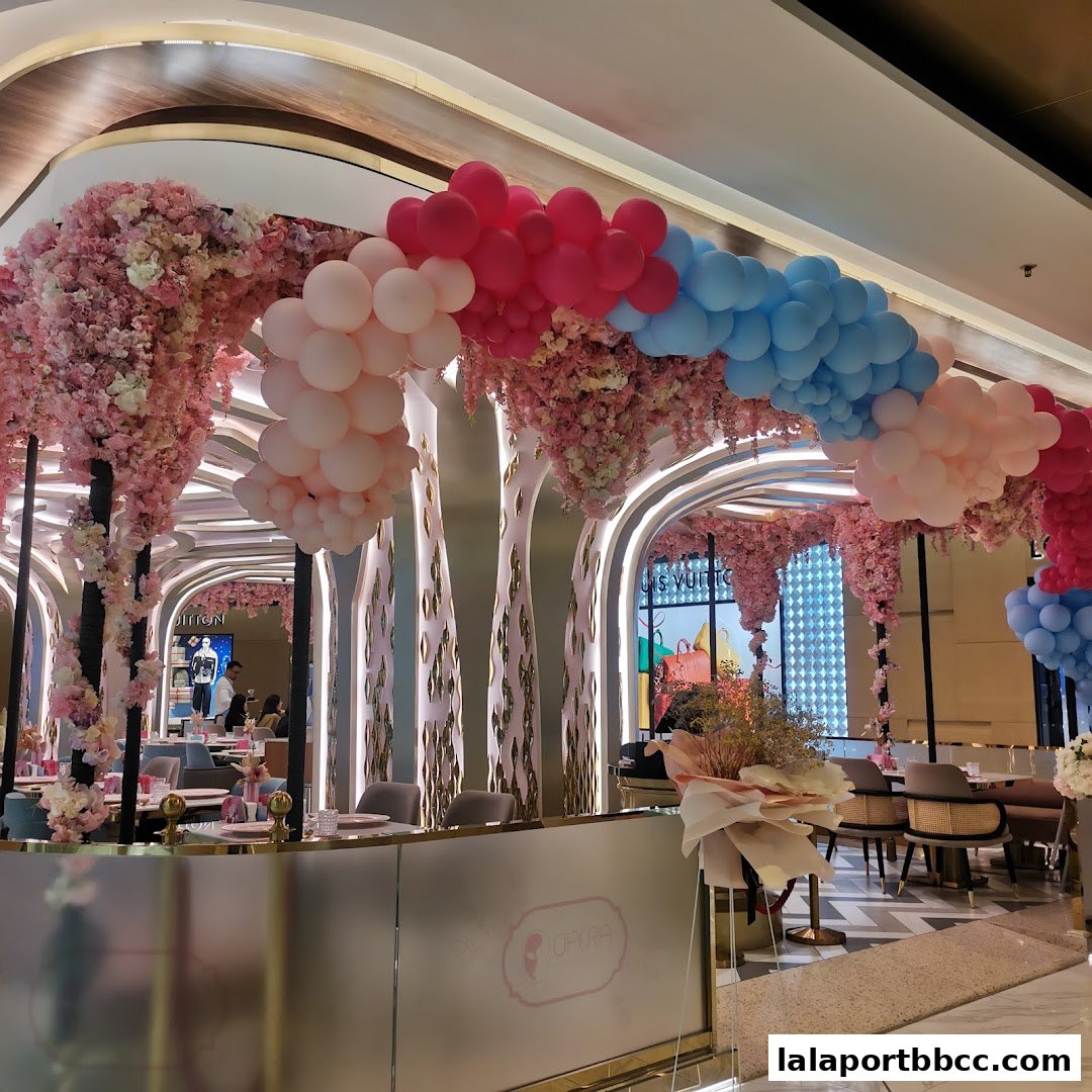 A beautifully decorated cafe interior with floral arches and balloons, creating a festive atmosphere.