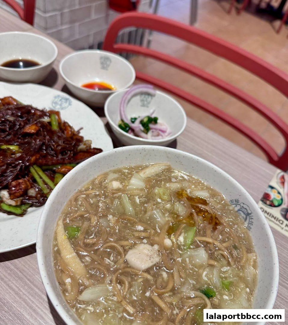 A close-up of two bowls of noodles and side dishes on a table.