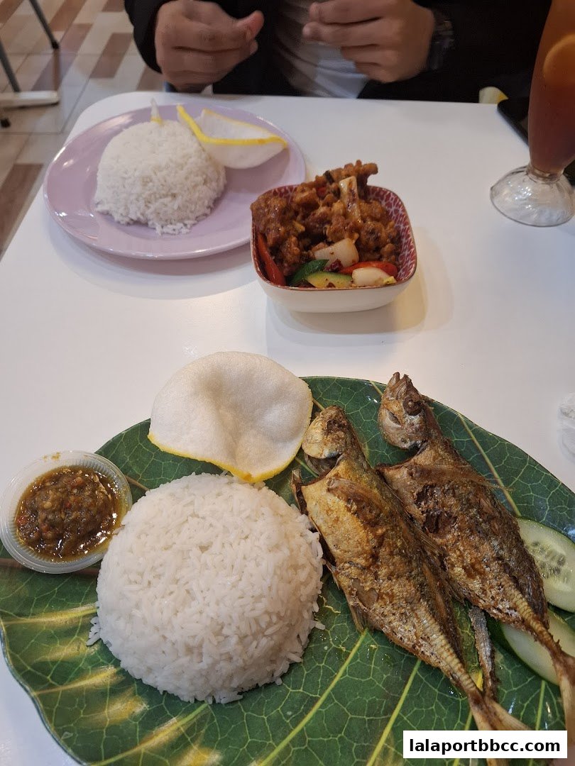 A table setting with two plates of food, rice, fried fish, and a drink.