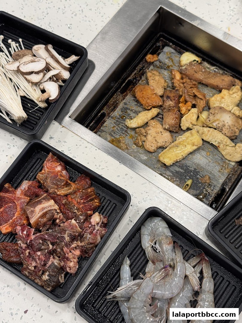 A close-up of Korean BBQ ingredients including raw beef, shrimp, mushrooms, and cooked meats on a grill.
