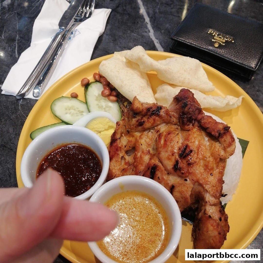 A delicious plate of Nasi Lemak with grilled chicken, served with sambal and peanut sauce.
