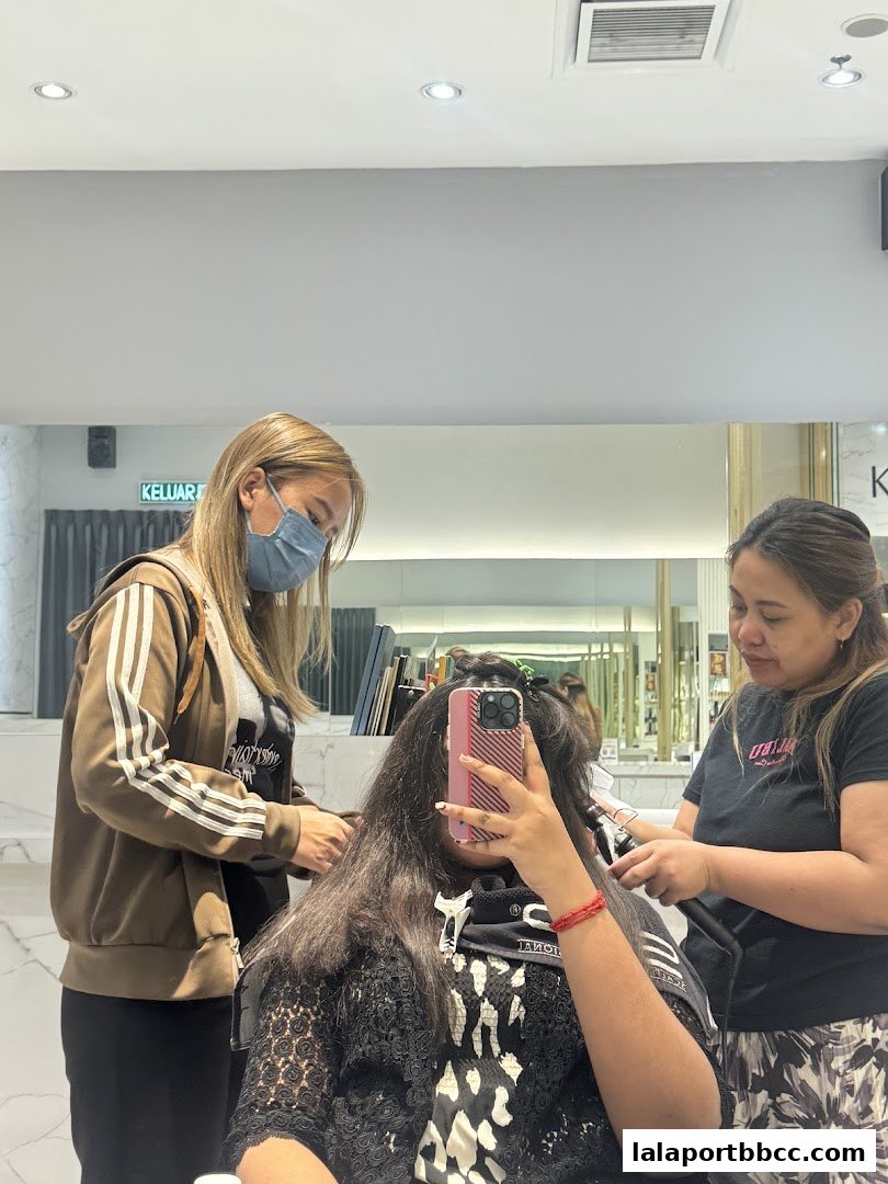 Two stylists are working on a client's hair inside a modern salon.