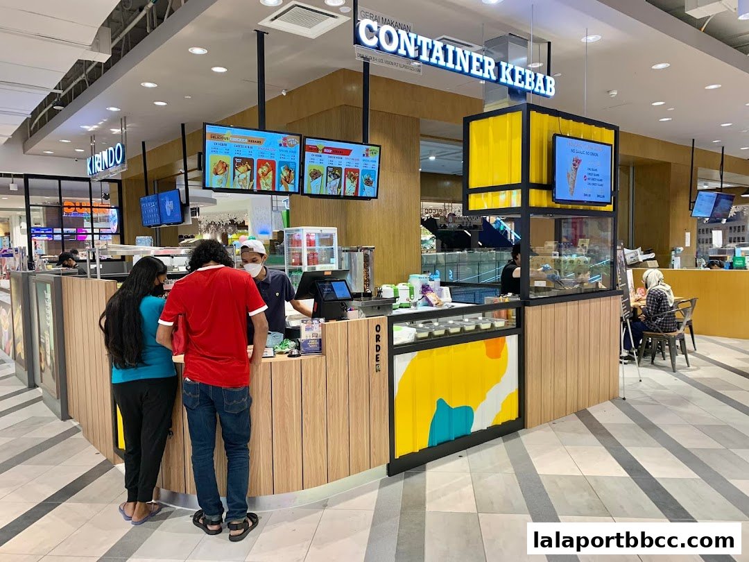 Customers ordering at the Container Kebab food stall with digital menus displaying food items.