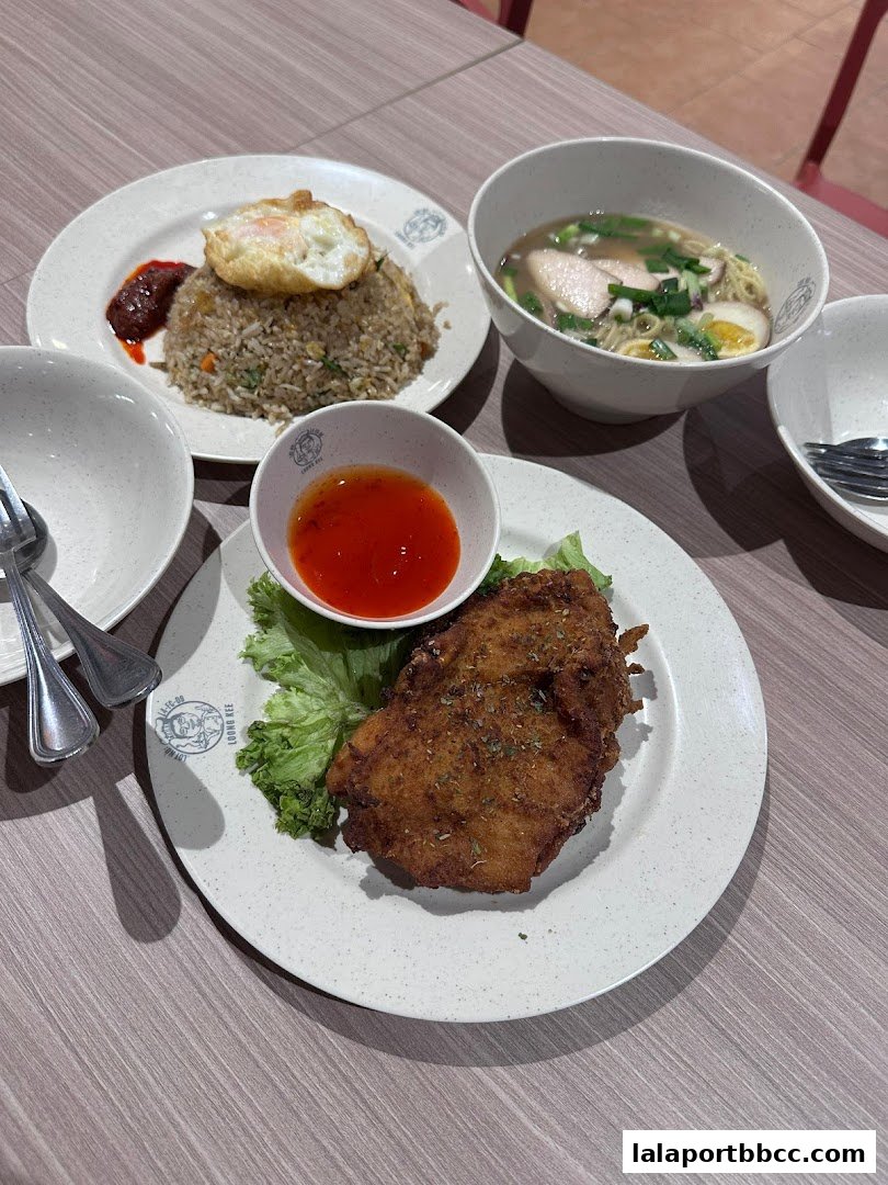 A table setting with fried chicken, fried rice with a fried egg, and a bowl of noodles.
