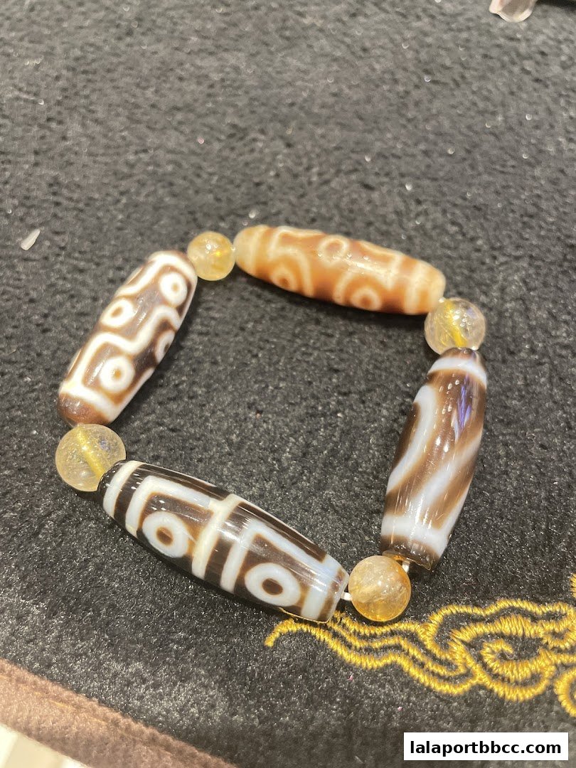 A close-up of a bracelet featuring Dzi beads and citrine stones.