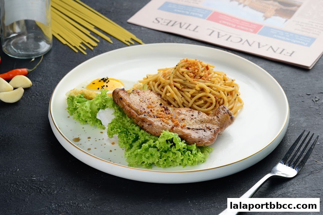 A plate of spaghetti with grilled meat and a fried egg, served with lettuce.