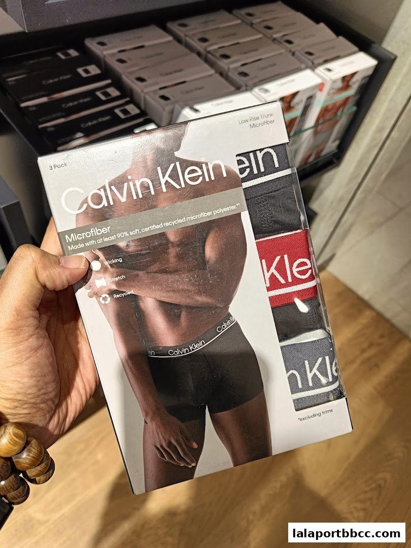 A hand holds a 3-pack of Calvin Klein microfiber low-rise trunks.
