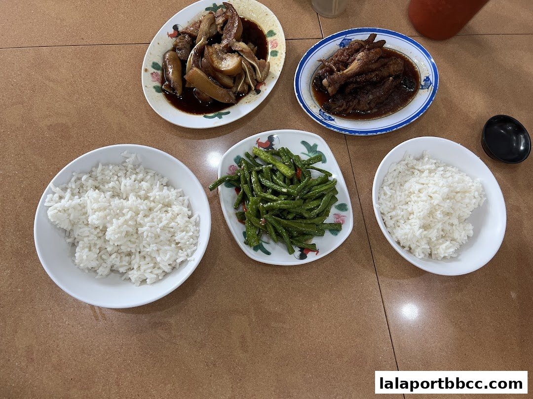 A table laden with Teo Chew dishes including braised pork, chicken feet, stir-fried beans, and rice.