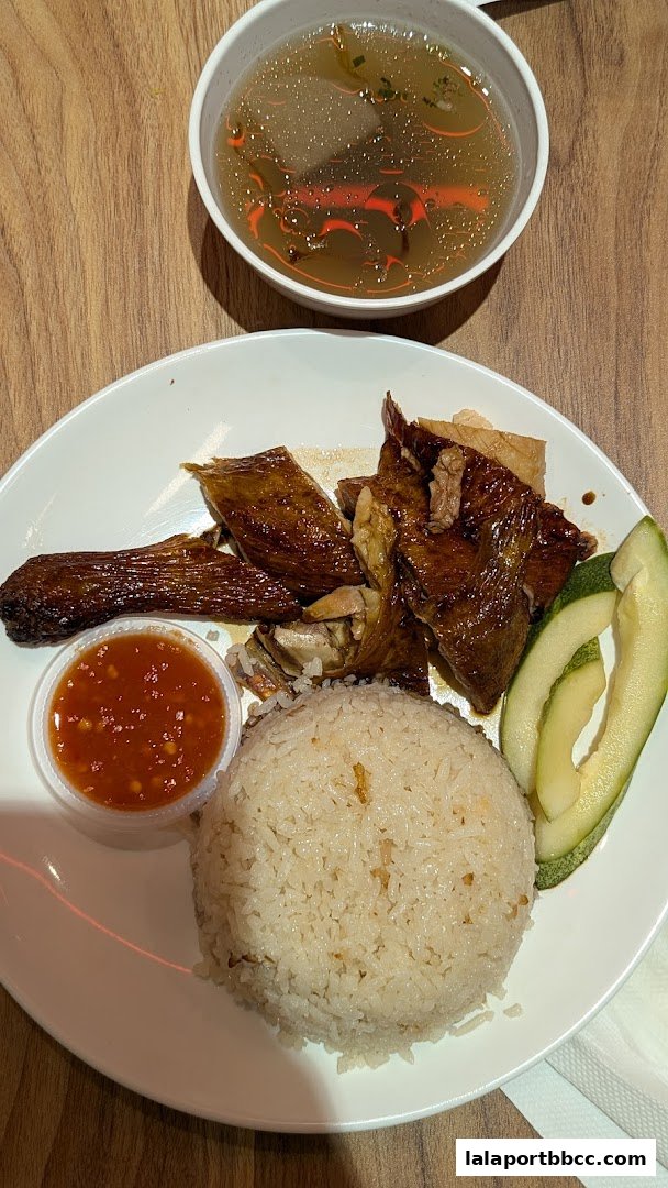 A plate of delicious chicken rice with soup and chili sauce.
