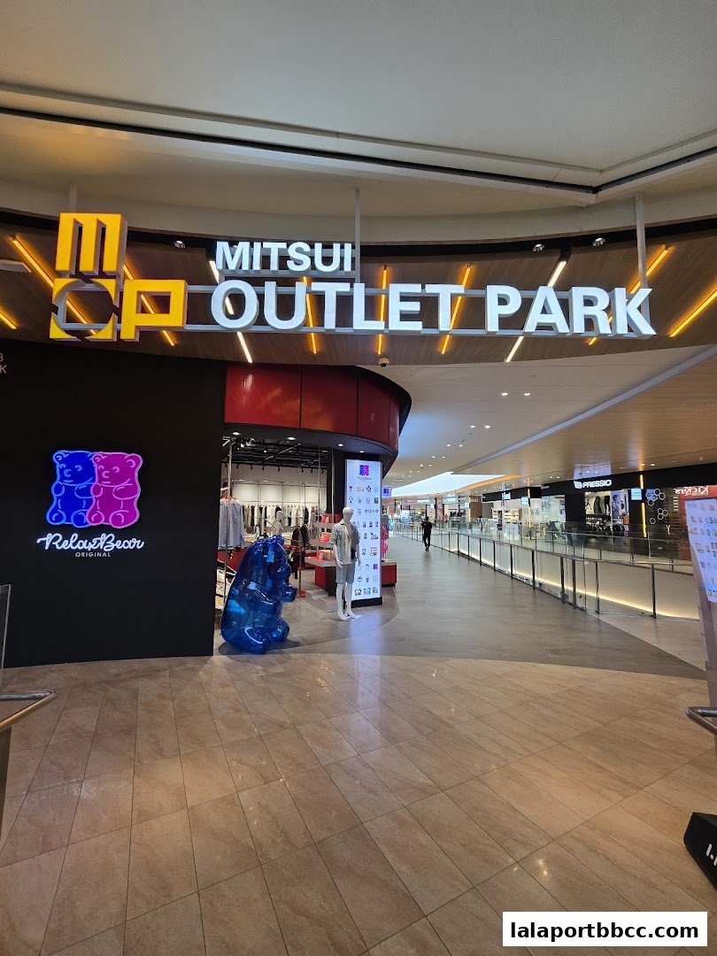 The entrance to Mitsui Outlet Park with prominent signage and a large blue gummy bear sculpture.
