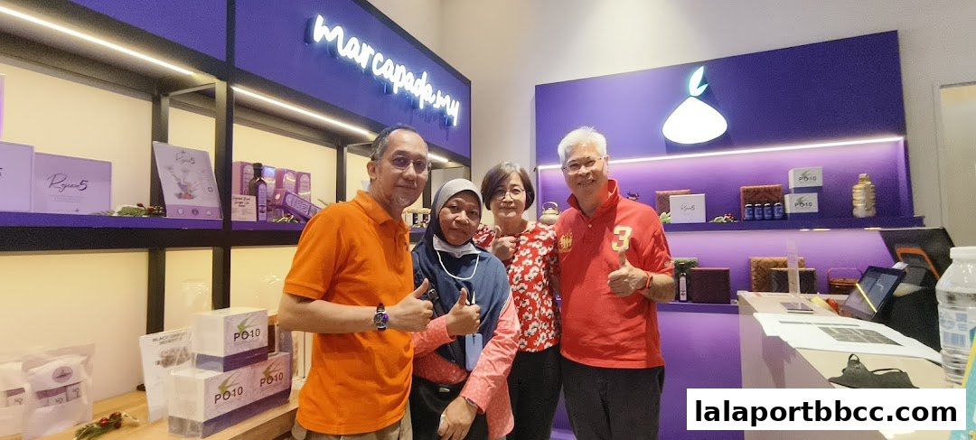 Four people posing in front of a shop with purple shelving and products.