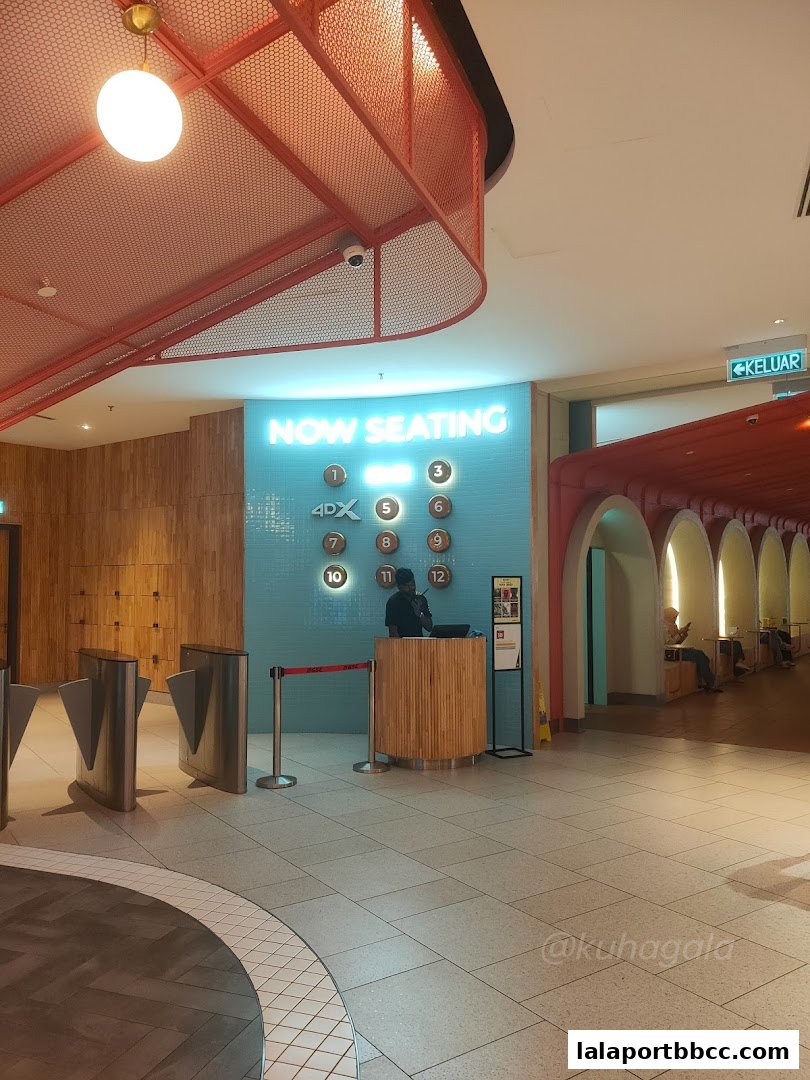 Entrance area of a cinema with ticket gates and a "Now Seating" display.
