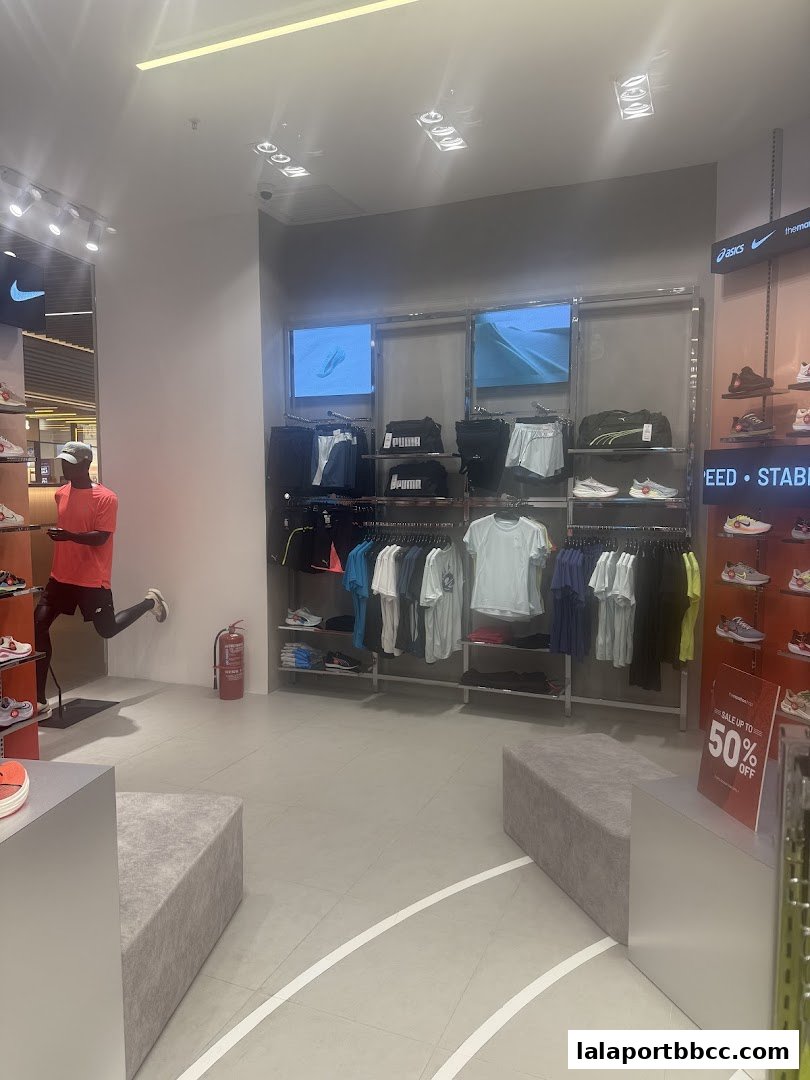 Interior of a sports apparel store with clothing, shoes, and a mannequin.