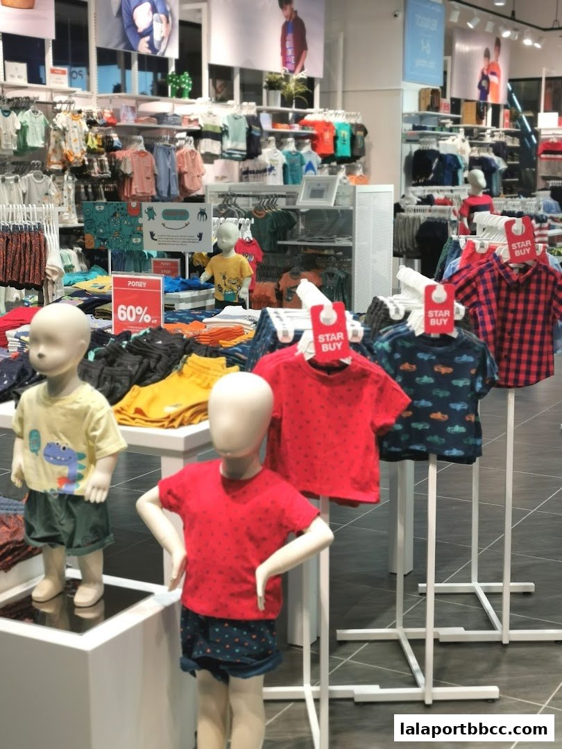 Children's clothing store interior with mannequins displaying outfits and sale signs.