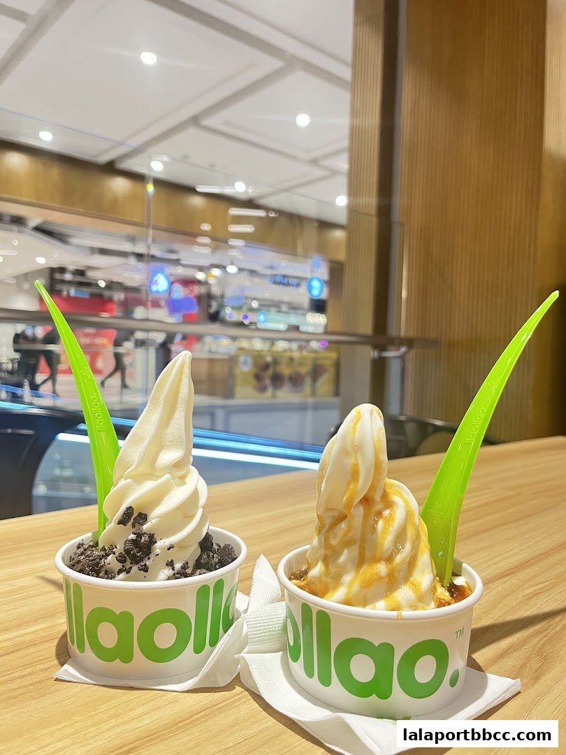 Two cups of llaollao frozen yogurt with toppings on a wooden table.