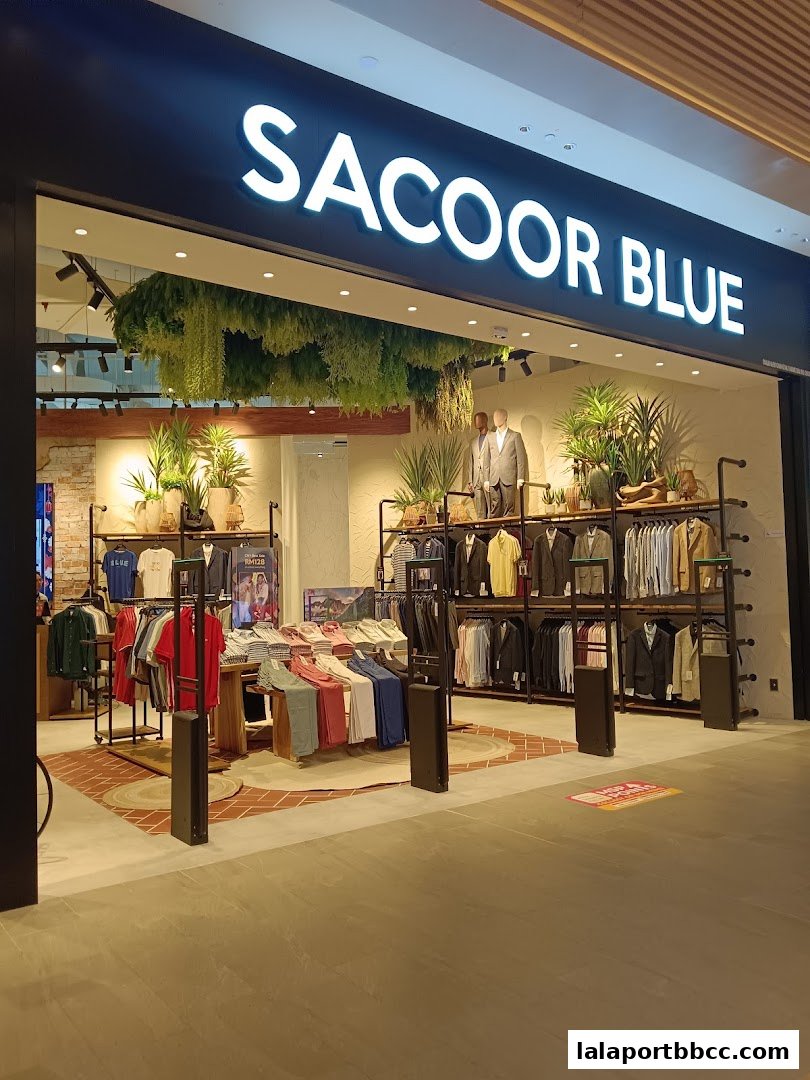 The Sacoor Blue store entrance displays a variety of men's clothing and mannequins.