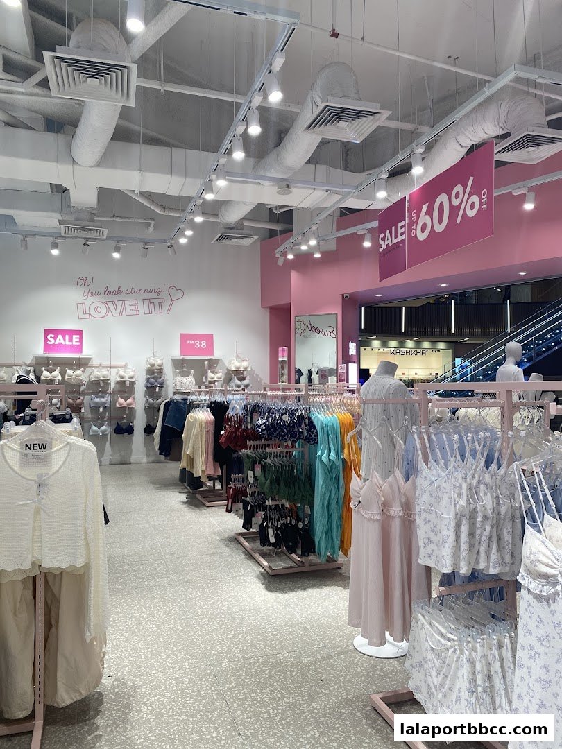 Interior view of a brightly lit clothing store with racks of lingerie and apparel, featuring sale signs.