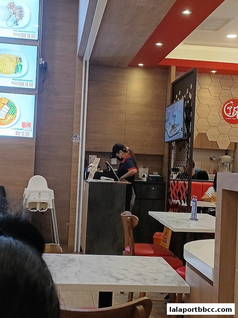 Interior of a restaurant with a staff member at the counter and tables.