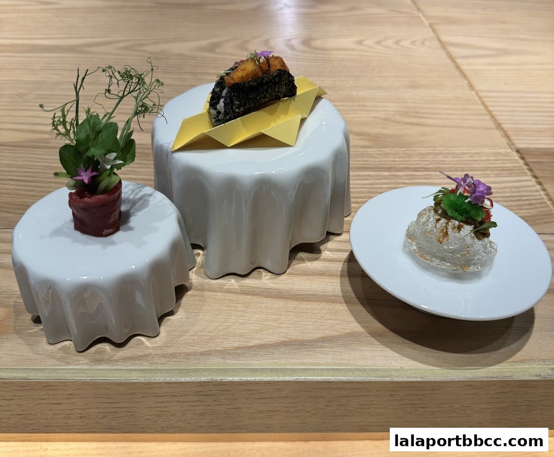 Three artfully presented small dishes with delicate garnishes on a wooden surface.
